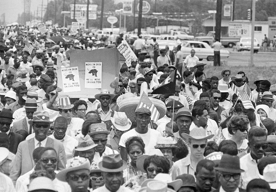 A group of marchers carrying placards walks through a street in Jackson