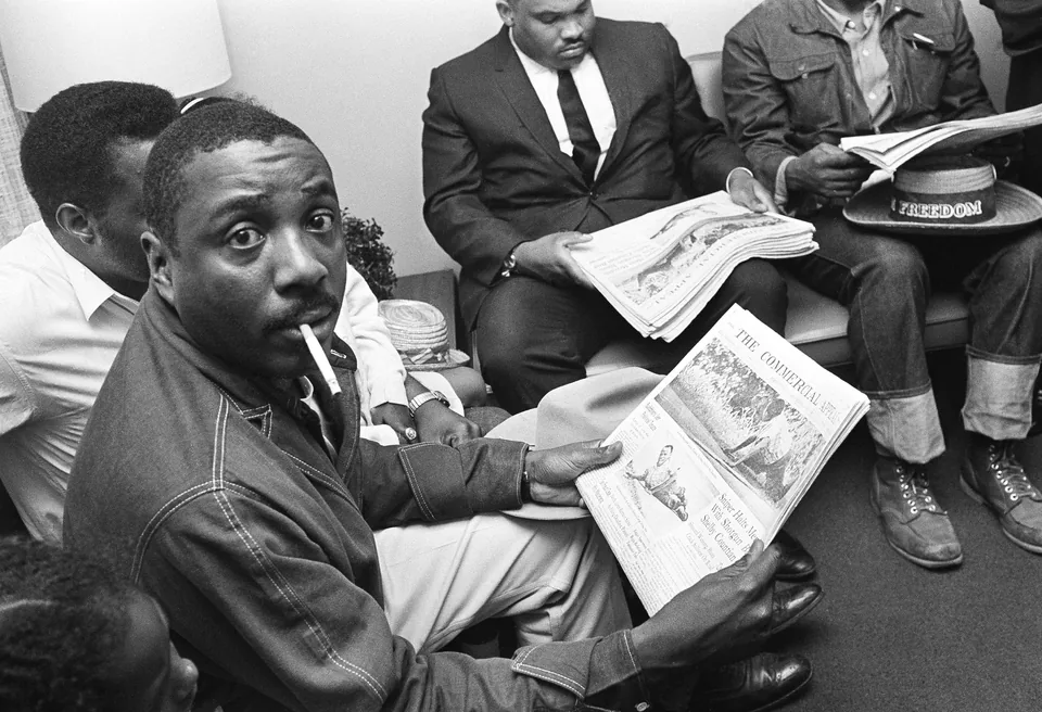 Dick Gregory sits in a hospital reading a newspaper