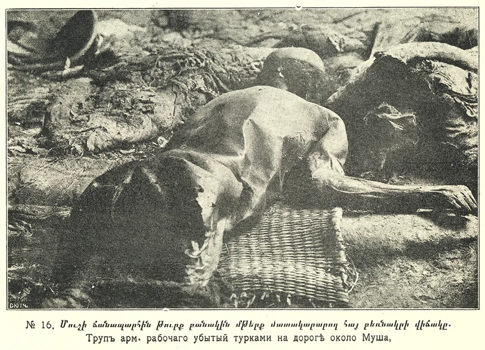 A man’s body lies among stones beside a road