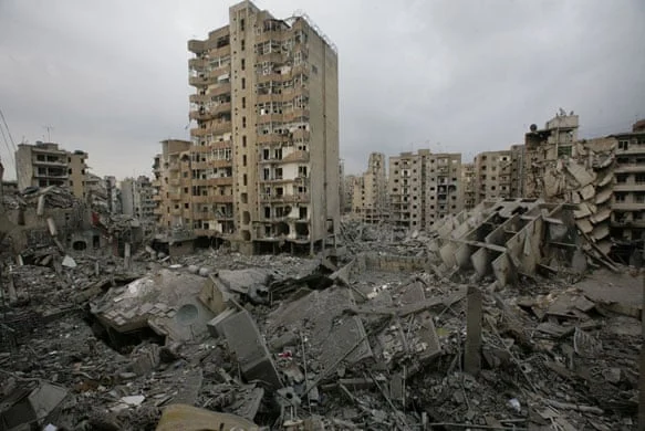 Piles of rubble beside damaged apartment buildings.