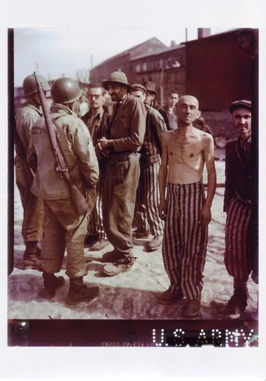 An emaciated shirtless man stands among people in the Little Camp