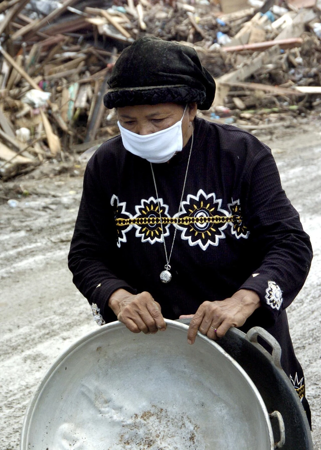 A woman collects bowls beside her damaged home. Banda Aceh, 14 January 2005.