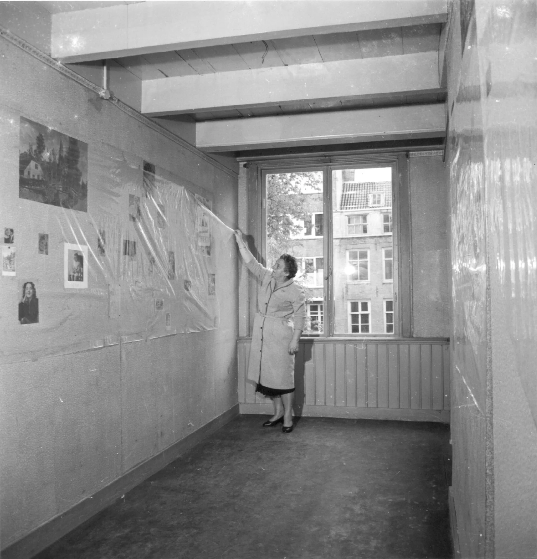 Truus Wijsmuller removes protective covering from the pictures on Anne’s wall. Amsterdam, before the museum opened on 3 May 1960.