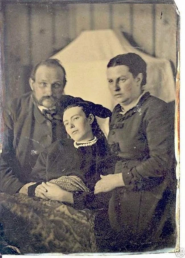 A young woman sits between a man and a woman. Online collections call her a deceased daughter between her parents, but no archival record has been found to confirm their identities, relationship or a post-mortem sitting.