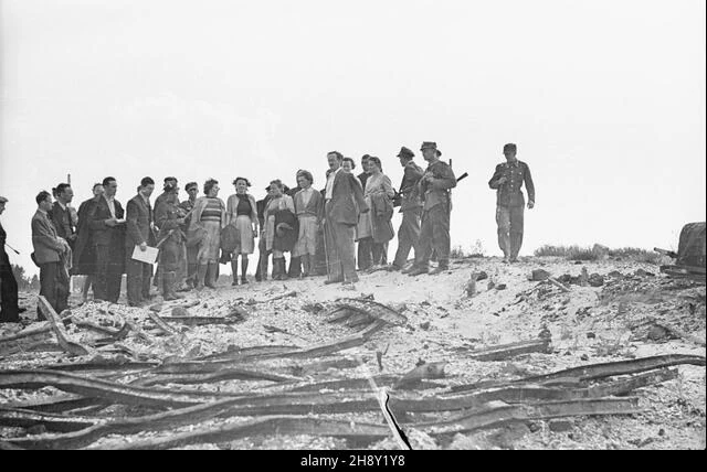 The inspection party stands beside a platform with metal grates. The agency caption calls it a place where bodies were burned; the order of the exposures is unknown.