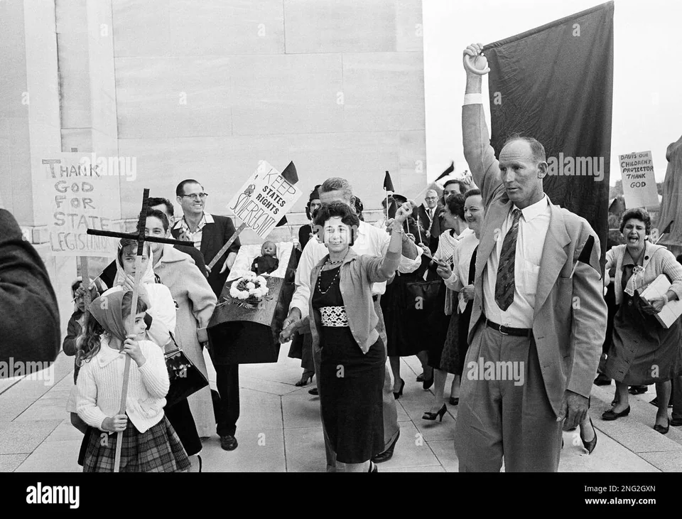 The group beside the Capitol wall. A man holds a large black banner; the doll’s coffin is visible behind him.