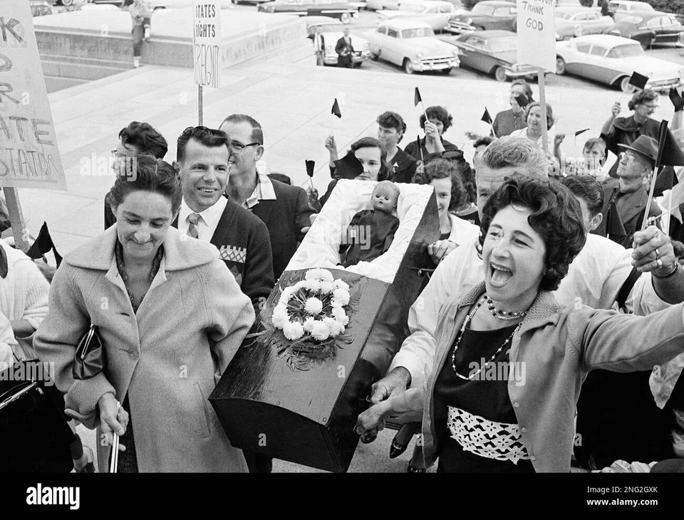 Opponents of school integration carry a coffin holding a doll up the steps of the Louisiana State Capitol. Baton Rouge, 23 November 1960, according to the Associated Press caption.