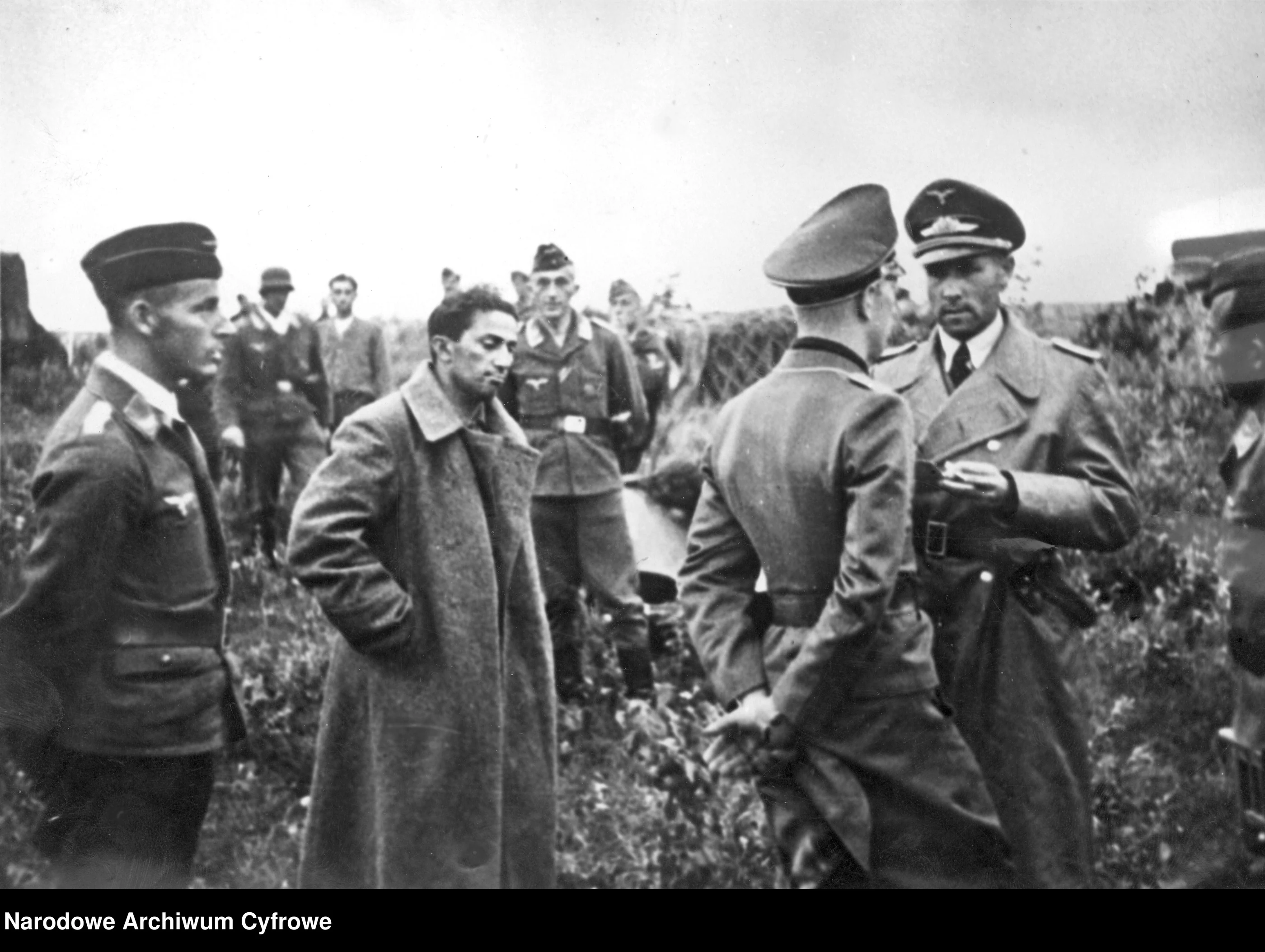 Yakov Dzhugashvili among German servicemen at a field airstrip. Poland’s National Digital Archives dates the image to July 1941 and says he was about to be sent for interrogation.